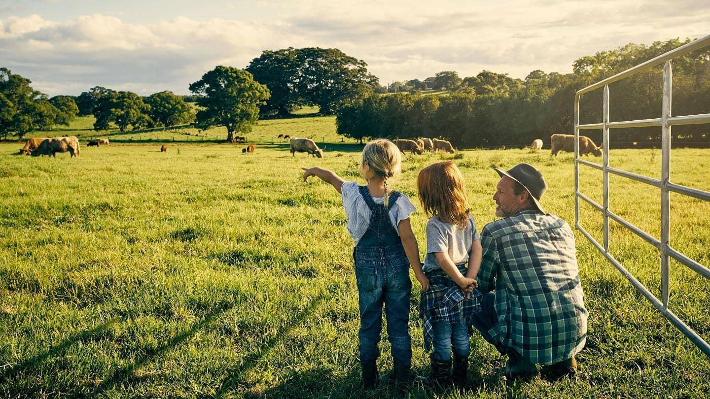 Two young girls and their father looking over their cattle farm