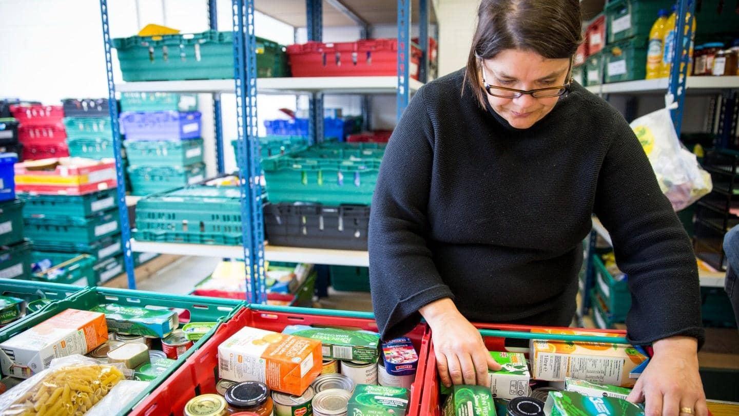 A volunteer is sorting through various food donations in the food bank warehouse