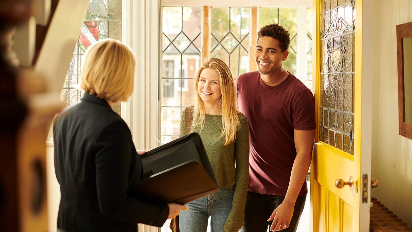 A couple standing in a hallway with an estate agent for a house viewing