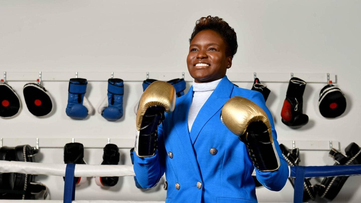 Nicola Adams, ex-Olympic boxer, in a boxing ring wearing a cyan blue suit and gold boxing gloves