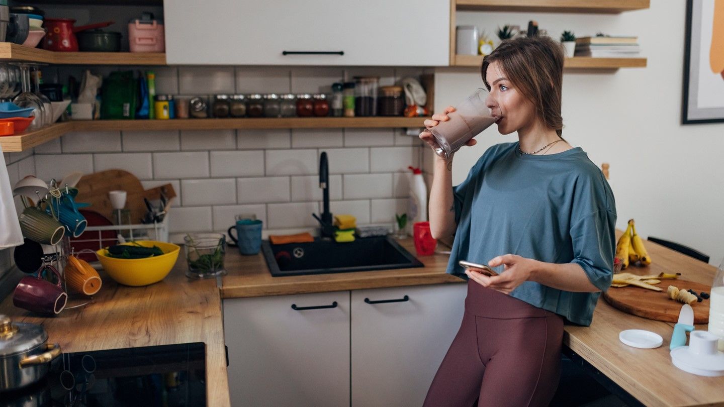 Woman drinking smoothie in kitchen