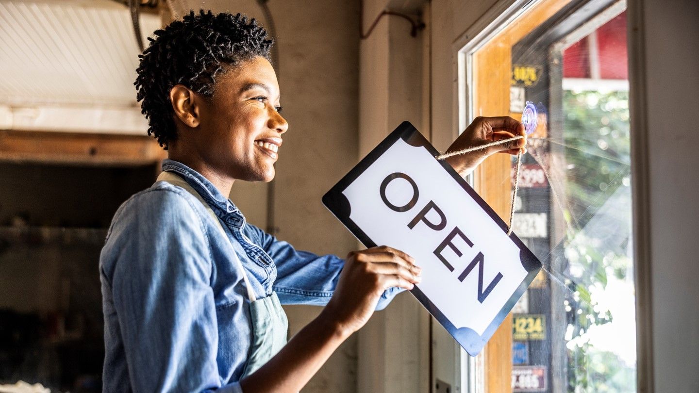 Smiling woman besides 'open' sign