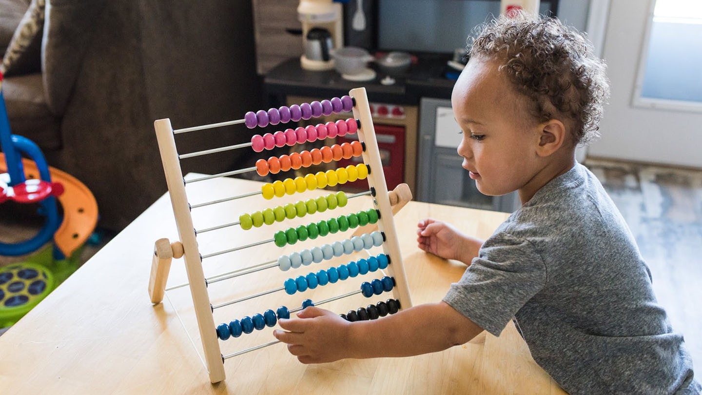 Young child playing with abacus counting frame. 