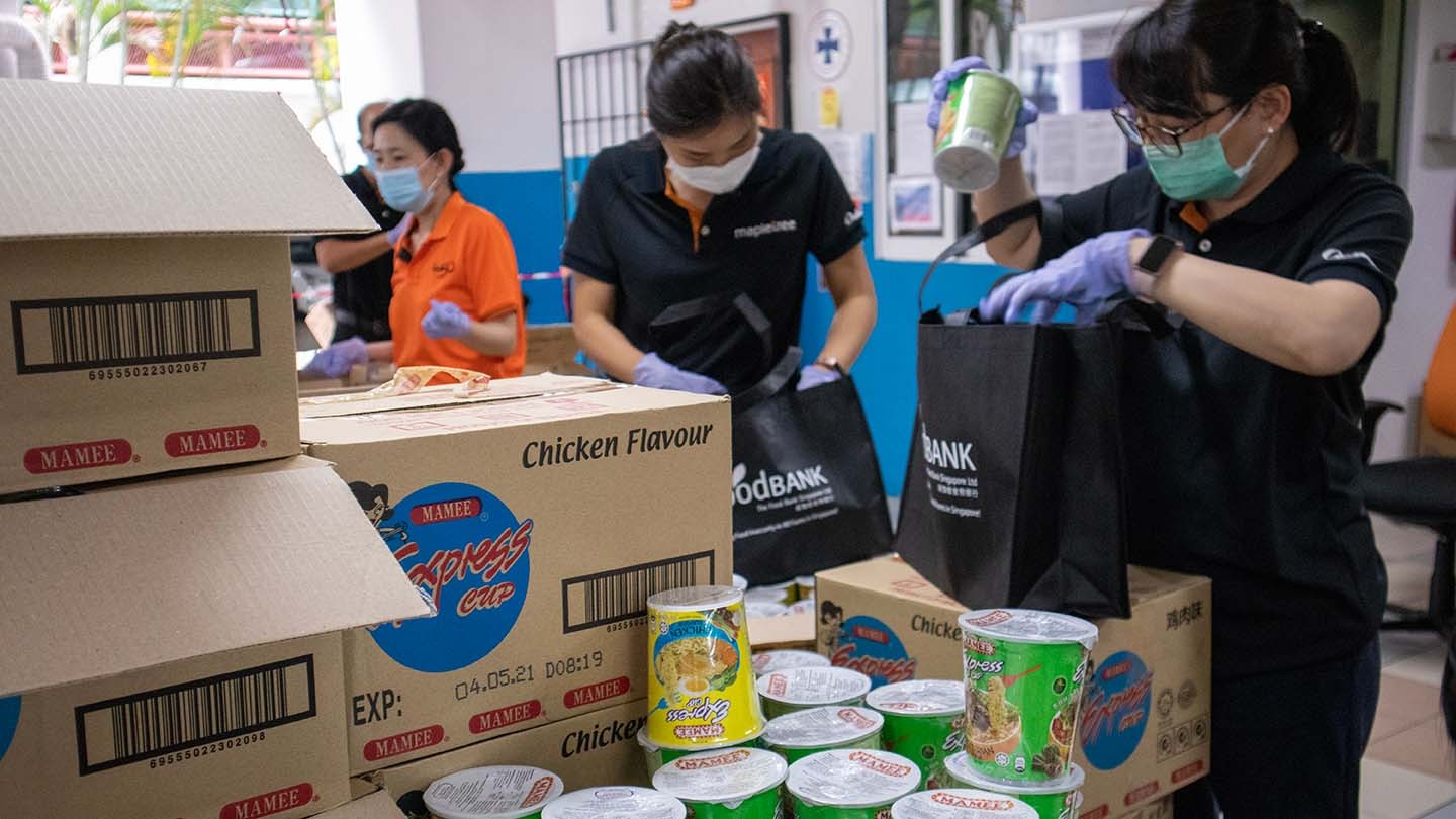 The Food Bank Singapore volunteers unload boxes of food from a van.