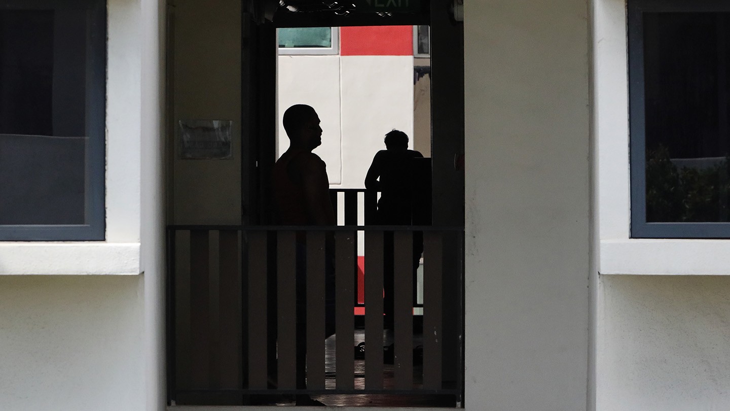 Silhouettes of two men in a migrant dormitory. 