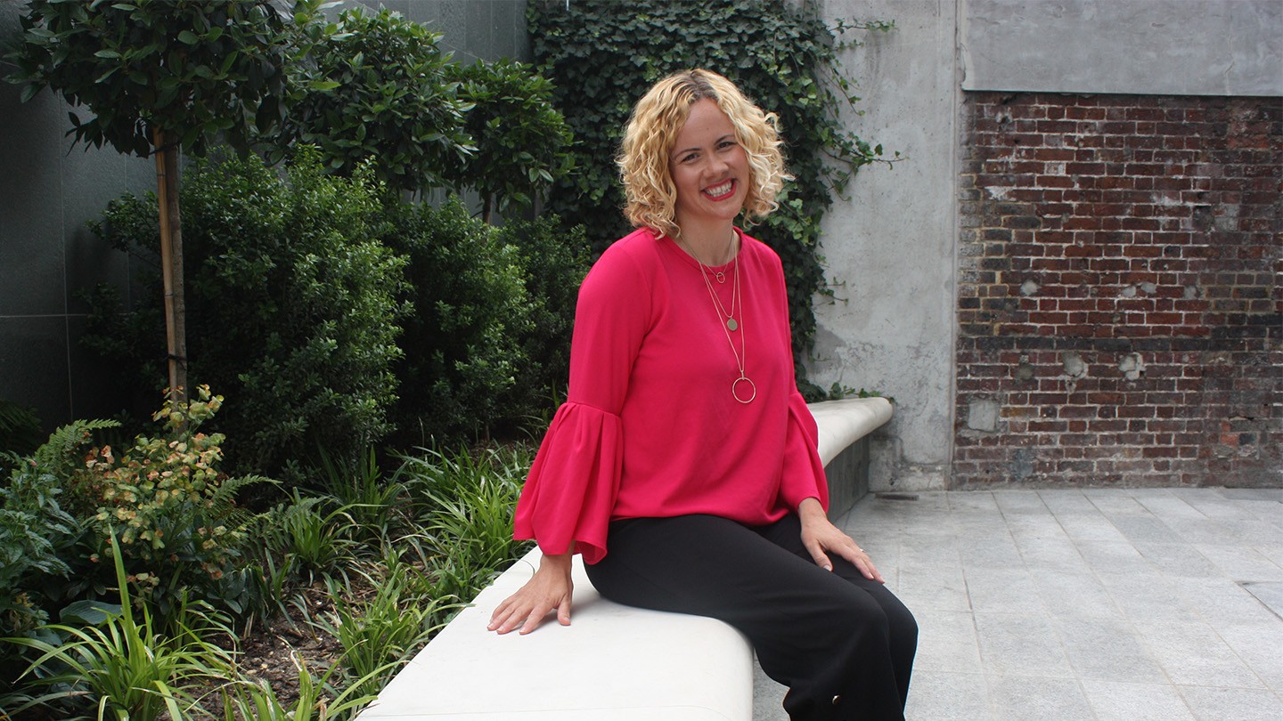 Mari Edwards smiles for a photo, sitting on an outdoor bench.