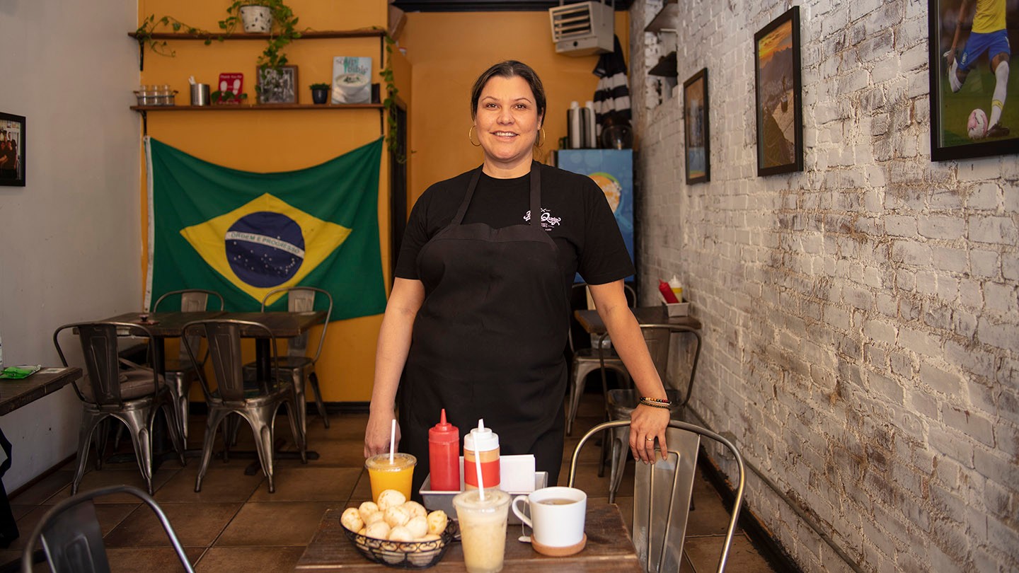 Karina stands beside a table in her Brazilian restaurant. 
