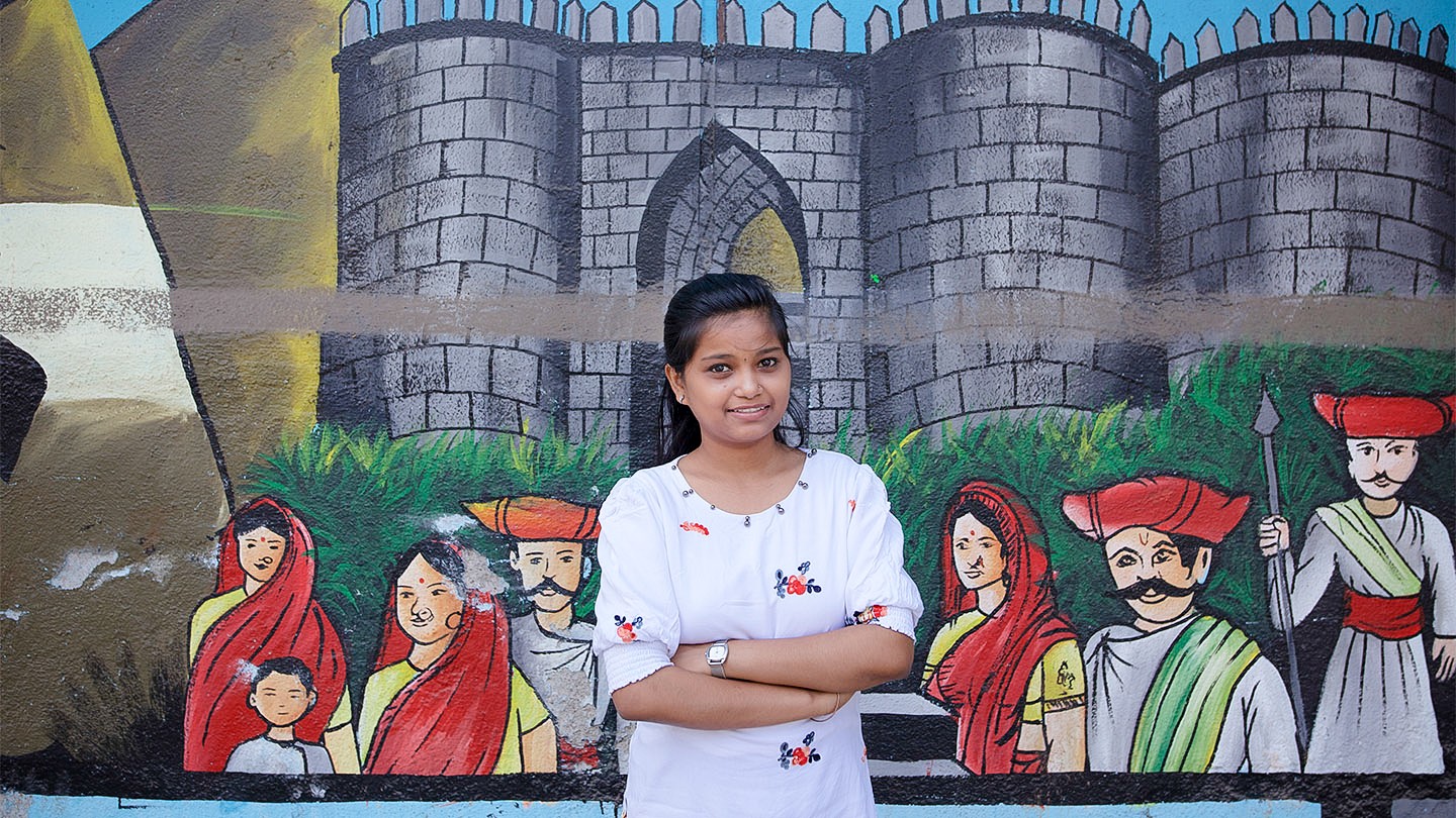 Yogita Jadhav standing in front of street art in Pune, India