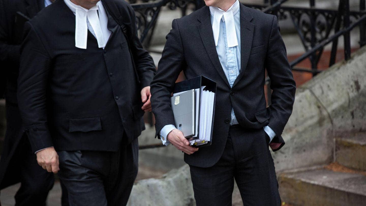 Two lawyers, one of them carrying a book and laptop.