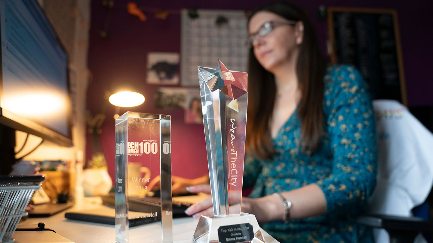 Barclays’ Emma Horsfall displays two awards while working at her home office desk.  