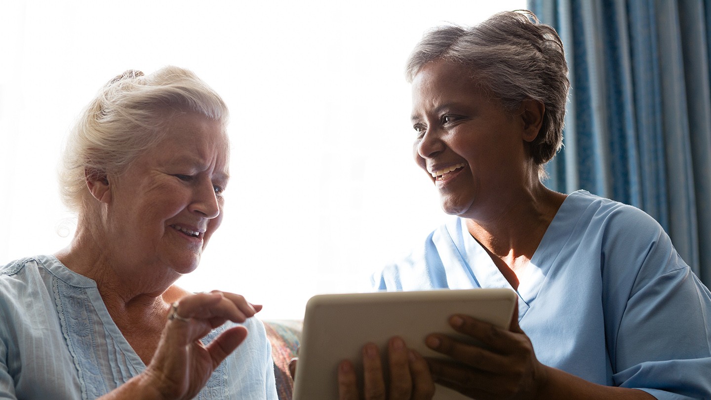 Two women look at a tablet.