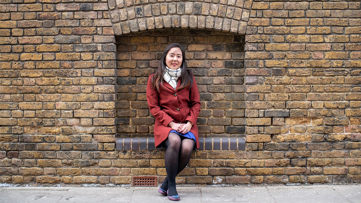 Emily Li sitting on a brick wall.
