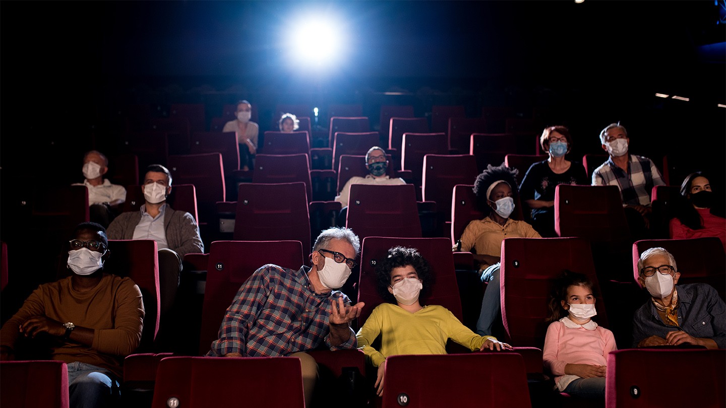 A cinema with a socially distanced audience, wearing masks.