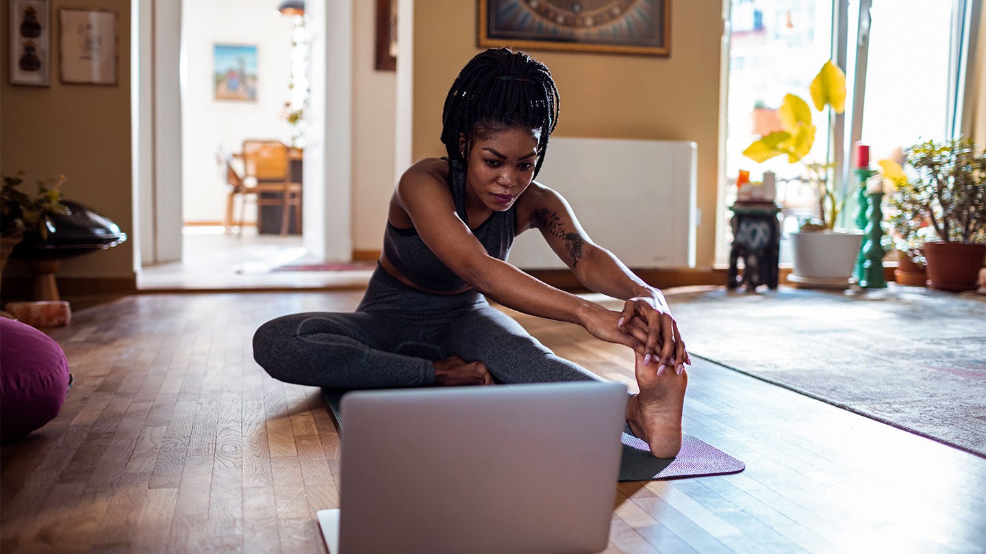 A woman stretching in front of a laptop.
