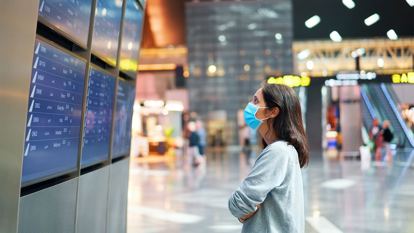 Woman staring at airport arrival/departure boards.