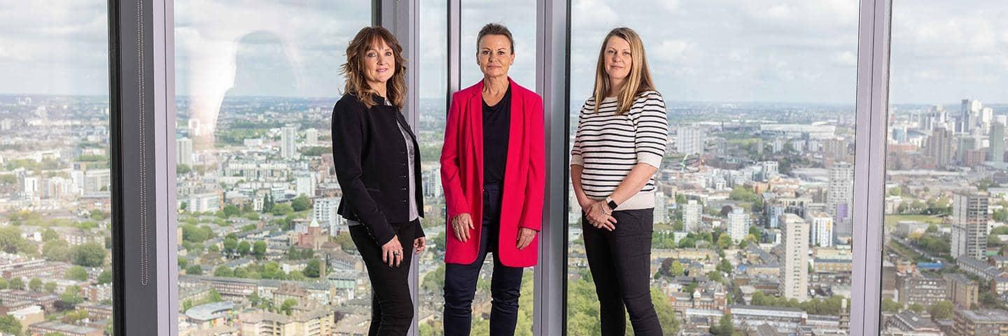 An image of Barclays’ May Mackay, Alison Stanley and Rachel Webster standing by an office window.