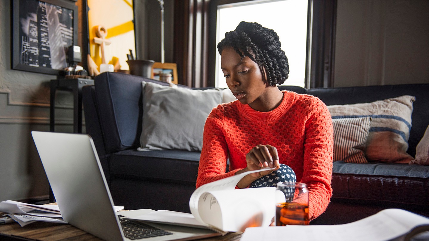 Black woman working from home in front of laptop wearing bright red jumper